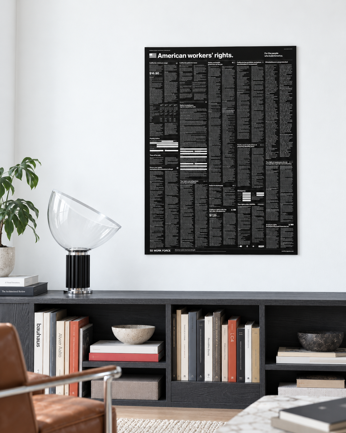 Unframed Modern Black 30×40 California and federal labor law poster above a charcoal bookshelf and sculptural glass lamp in a bright white interior.